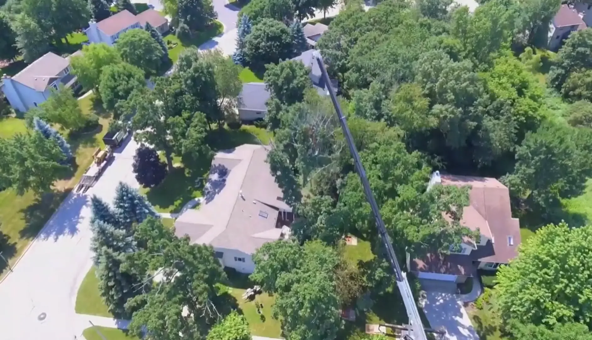 Tree fell on house roof in Rome, GA — crane boom extended over a house roof to remove a large tree near the structure